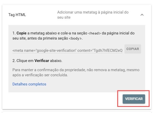 Captura de tela de uma página de verificação de propriedade do Google, com instruções em português para adicionar uma meta tag ao HTML do site. O primeiro passo orienta o usuário a copiar a meta tag <meta name="google-site-verification" content="Tgdh7hfECM2eQ"> e colá-la na seção <head> da página inicial do site, antes da primeira tag <body>. Ao lado da meta tag há um botão "COPIAR" para facilitar a ação. O segundo passo instrui o usuário a clicar no botão "VERIFICAR", destacado em vermelho no canto inferior direito. Abaixo das instruções, há um aviso para não remover a meta tag após a verificação, a fim de manter a confirmação da propriedade, além de um link "Detalhes completos" para mais informações.