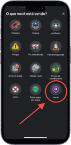 Captura de tela da interface de um aplicativo de navegação ou mapas em português, exibida em um smartphone. A tela apresenta diversos ícones com rótulos que representam tipos de alertas ou relatórios que o usuário pode enviar: "Trânsito", "Polícia", "Acidente", "Perigo", "Via interditada", "Faixa bloqueada", "Erro no mapa", "Tempo ruim", "Preço do combustível", "SOS", "Este gapo de mapa" (possível erro de digitação) e "Local", este último destacado com um círculo vermelho e uma seta apontando para ele. A imagem ilustra funcionalidades de colaboração em tempo real para melhorar a navegação e a segurança dos usuários.