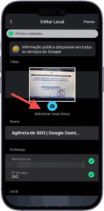 Captura de tela da interface de edição de local em um aplicativo móvel, exibida em português, possivelmente do Google Maps. No topo, há uma notificação "Pontos coletados" e a mensagem "Informação pública (disponível em todos os serviços do Google)", indicando que os dados inseridos serão visíveis publicamente. Abaixo, na seção "Fotos", há uma miniatura de imagem e o botão "Adicionar mais fotos", destacado por um ícone de câmera azul e uma seta vermelha. Em seguida, aparecem campos de edição como "Nome", preenchido com "Agência de SEO | Google Domi...", "Endereço", com o número da casa "242" e campo vazio para o nome da rua, além da seção "Local", também não preenchida. A imagem representa o processo de atualização de informações comerciais em uma plataforma de mapas, com foco em visibilidade pública e precisão de dados.