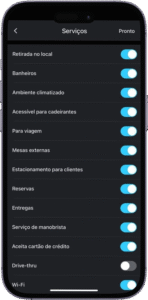 Captura de tela da interface de um aplicativo móvel em português exibindo a seção "Serviços", com uma lista de comodidades disponíveis em um estabelecimento. Cada item possui um botão de alternância indicando se o serviço está ativado (em azul) ou desativado (em cinza). Os serviços ativados incluem: "Retirada no local", "Banheiros", "Ambiente climatizado", "Acessível para cadeirantes", "Para viagem", "Mesas externas", "Estacionamento para clientes", "Aceita cartão de crédito", "Drive-thru" e "Wi-Fi". Os serviços desativados são: "Reservas", "Entregas" e "Serviço de manobrista". No canto superior direito, há o botão "Pronto", sinalizando que as configurações podem ser finalizadas. A imagem representa a personalização de informações comerciais em uma plataforma de cadastro ou mapeamento.