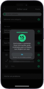 Captura de tela da interface de um aplicativo móvel em português, exibindo uma sobreposição de mensagem de confirmação sobre o formulário "Editar Local". A mensagem informa: "VOCÊ GANHOU 15 PONTOS. Você arrasou, querido! Suas informações serão mostradas para os Wazers que dirigem por aqui", com o botão "OK" abaixo e o texto adicional "Pendente de construções pendentes". Ao fundo, o formulário apresenta campos como "Nome do local", "Adicionar uma categoria" e "Serviços", todos com ícones de confirmação indicando preenchimento completo. A imagem representa a recompensa por contribuição de dados geográficos em uma plataforma colaborativa de navegação, incentivando o engajamento do usuário.